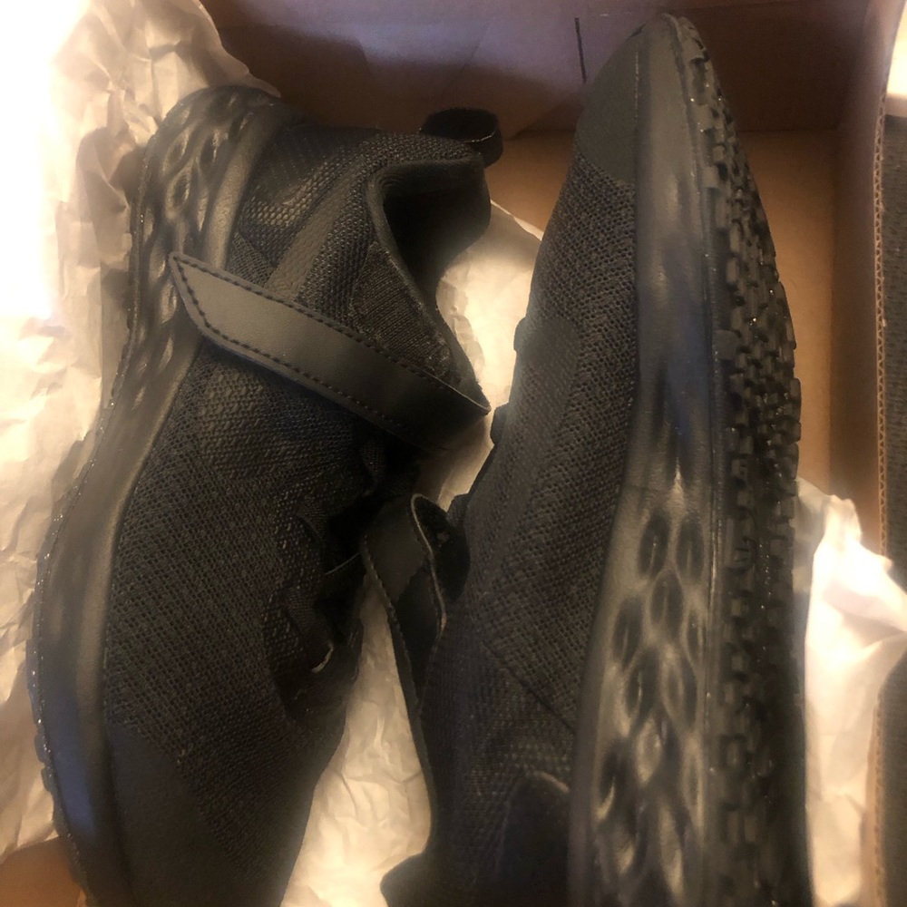These are black Nike sneakers with a strap on them in the size 1.5.